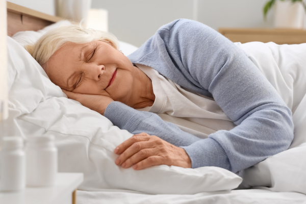 Mujer mayor durmiendo plácidamente en su cama, reflejando un descanso reparador y sin insomnio gracias a una adecuada asistencia domiciliaria en Navarra.